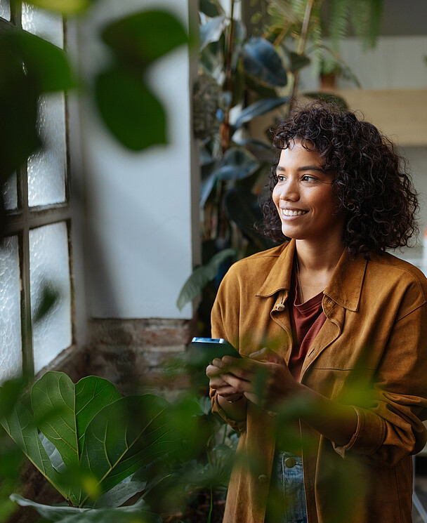 Une jeune femme entourée de plantes vertes profite de son nouveau logement
