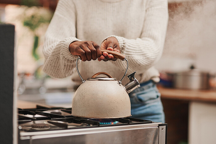 Une femme dans une cuisine porte une bouilloire