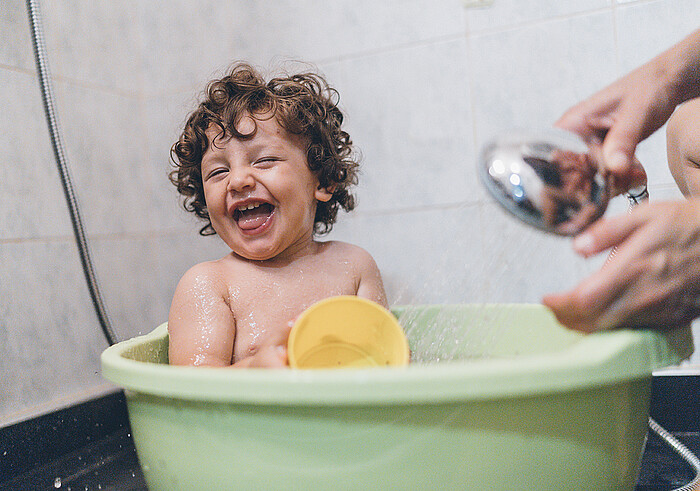 Un bébé rit dans son bain