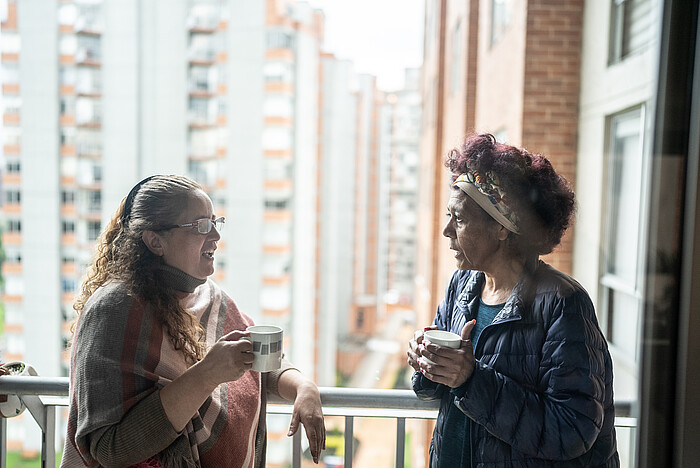 Deux voisines échangeant sur leur balcon dans une ambiance conviviale