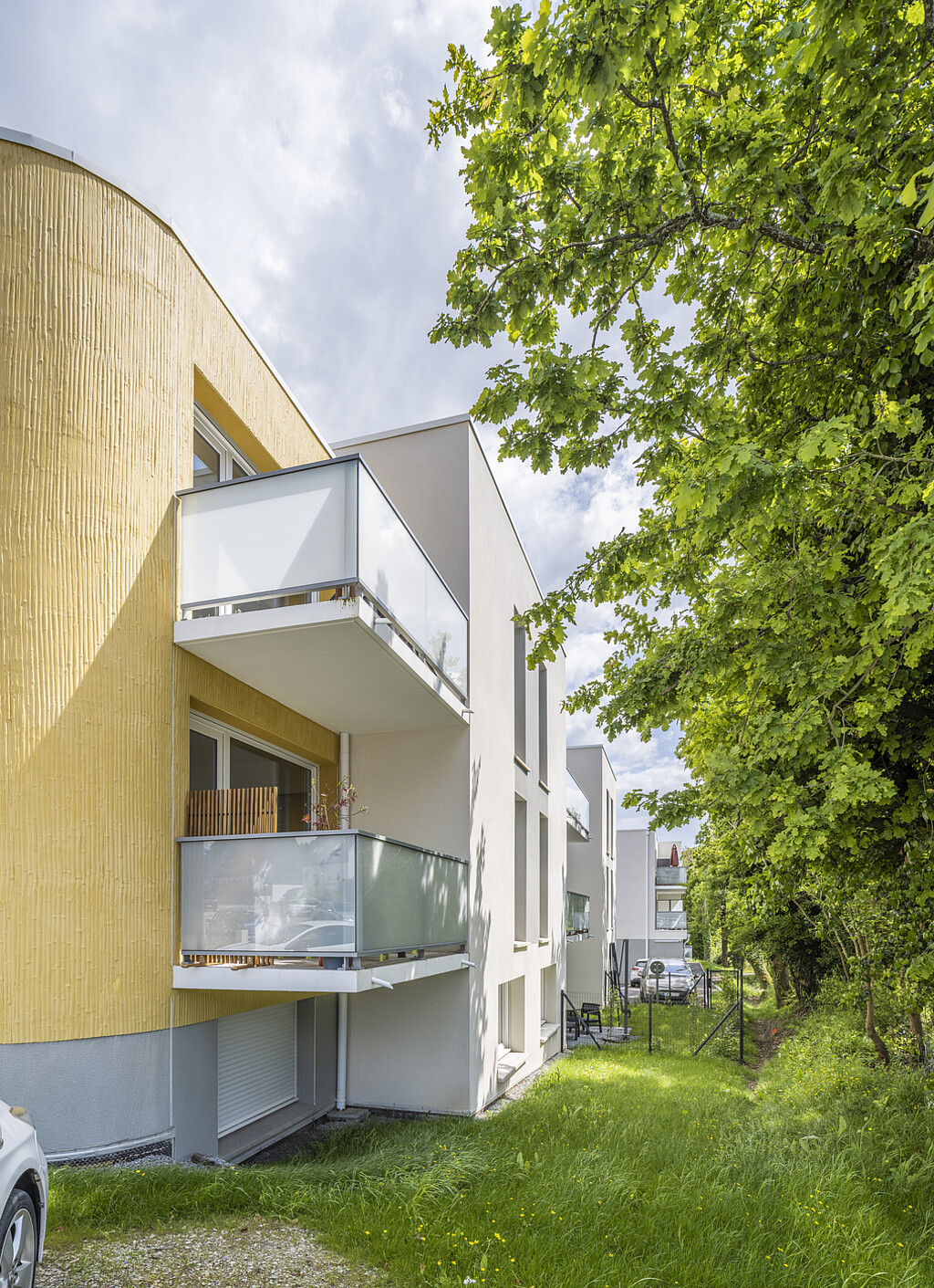 Jolie vue arborée des façade jaune et blanche de la résidence "Les Chouans" à Pluneret