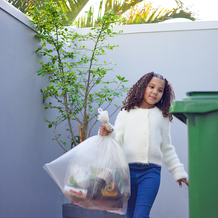 Petite fille déposant des déchets dans les conteneurs de tri sélectif
