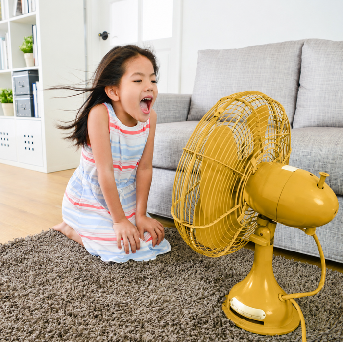 Une petite fille profite de l'air frais du ventilateur