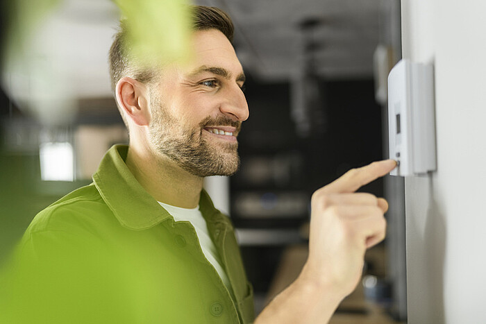 Un homme règle son thermostat