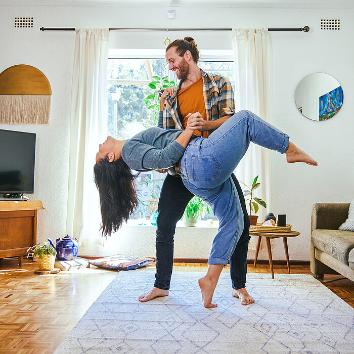 Un jeune couple heureux danse dans son salon