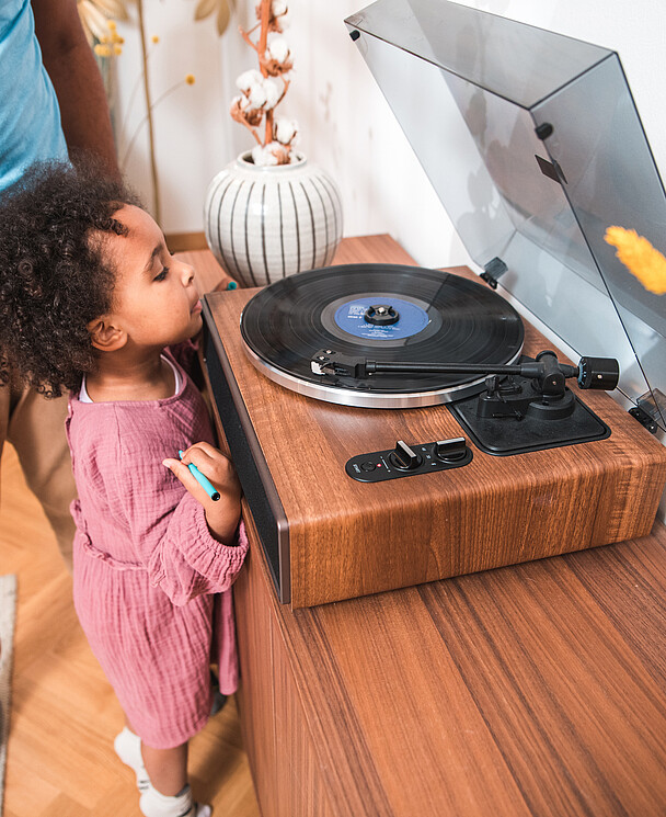 Une petite fille avec son papa regarde un disque vinyle tourner sur une platine